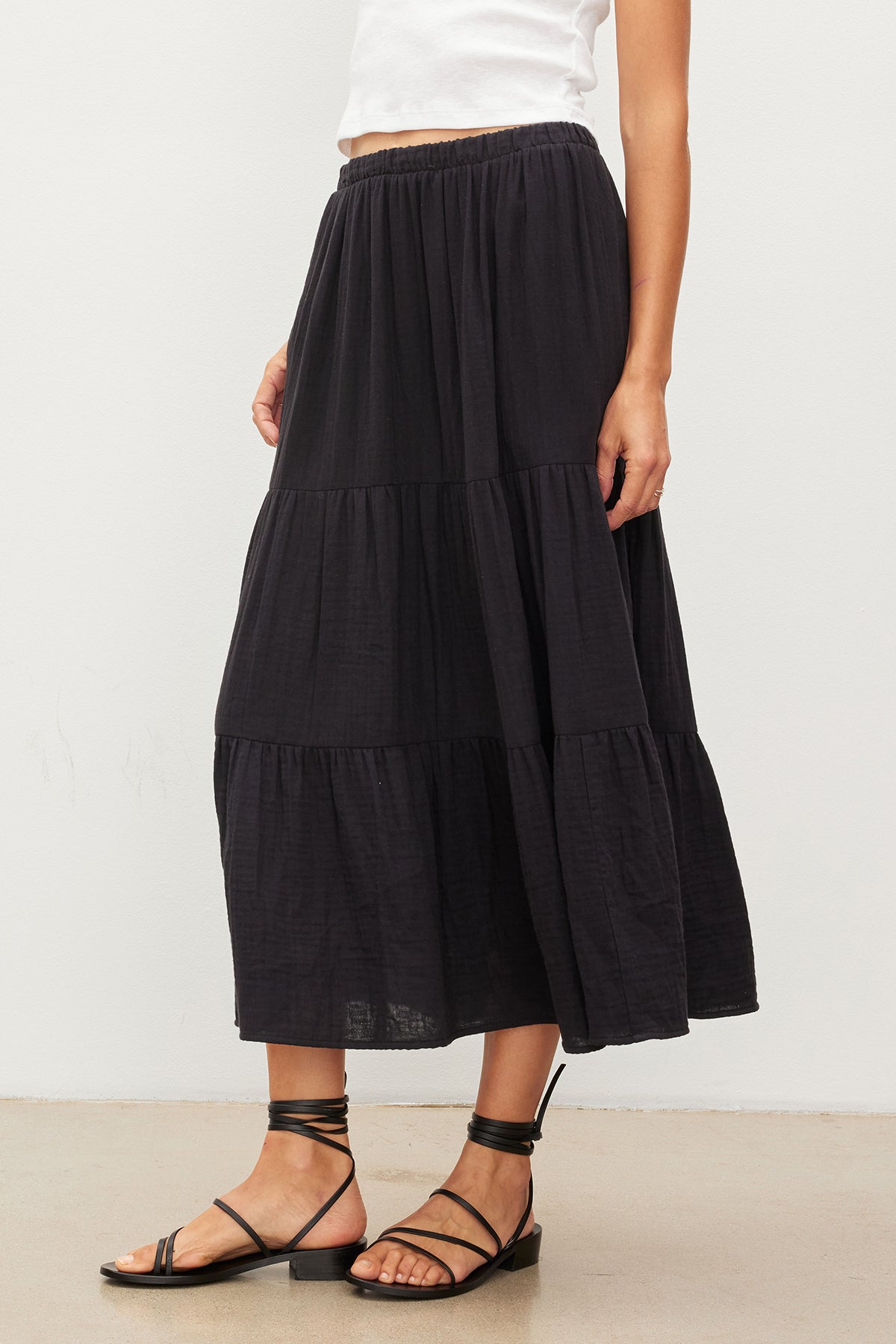   A woman wearing a black Velvet by Graham & Spencer Danielle Cotton Gauze Tiered Skirt with an elastic waist. 