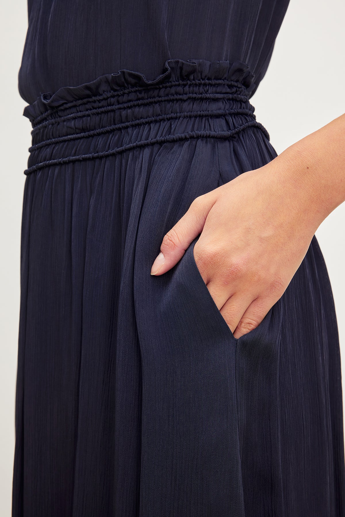  A person standing with their hand placed in the inseam pocket of a Velvet by Graham & Spencer DIMI SMOCKED SKIRT. 