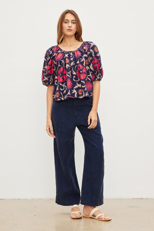 The stylish model is wearing a cool Velvet by Graham & Spencer navy floral top and wide leg pants.