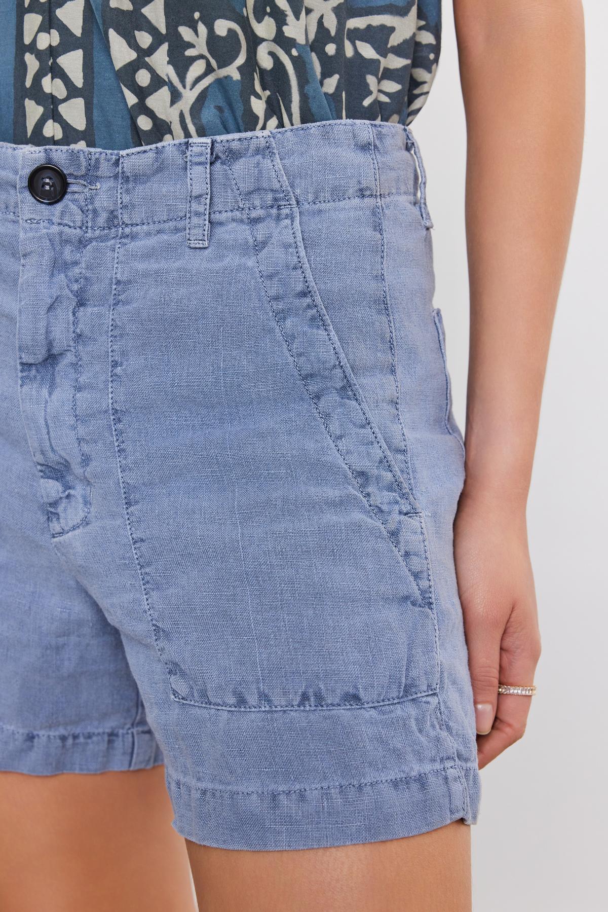   Close-up of a person wearing Velvet by Graham & Spencer's Fallon Heavy Linen Shorts with a distinctive diagonal seam design on the front. 