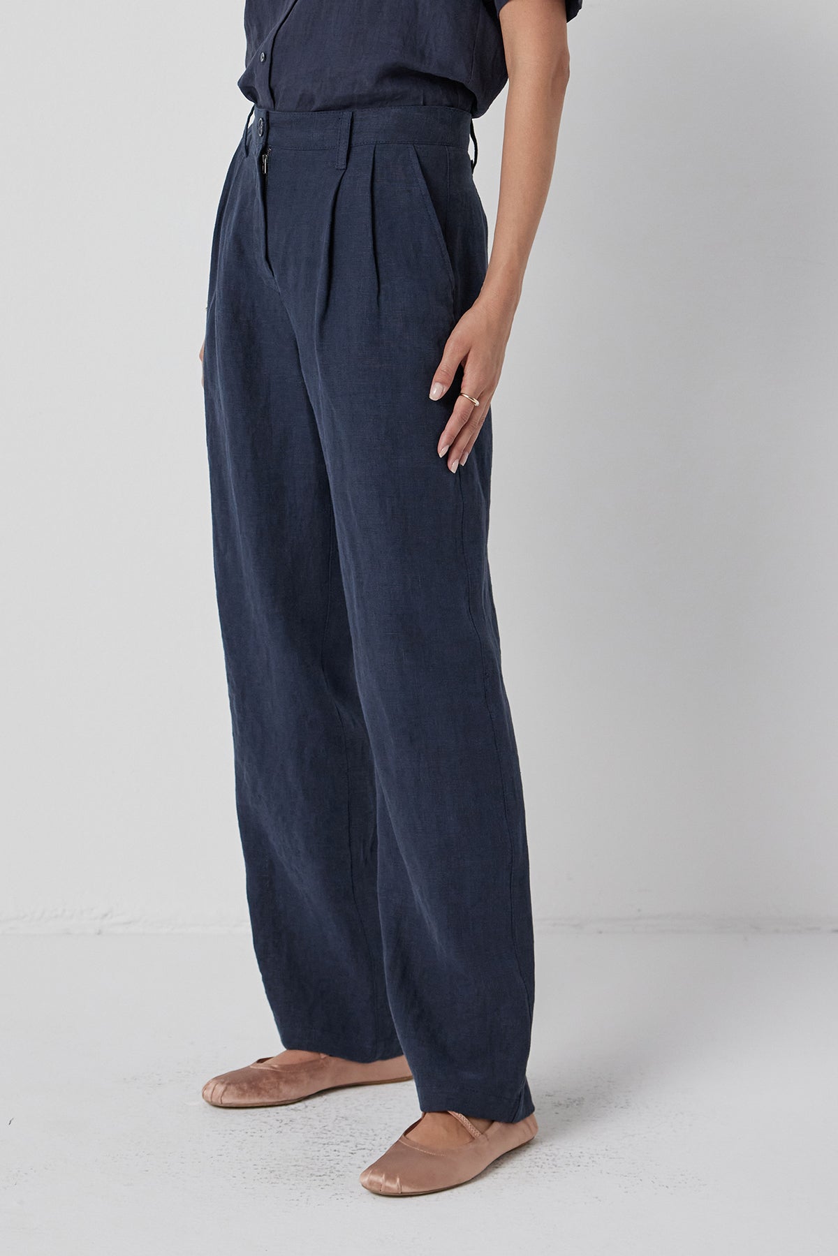   Woman in Velvet by Jenny Graham's POMONA PANT, dark, heavy-weight linen straight-leg pants and tan flats standing against a white background. 