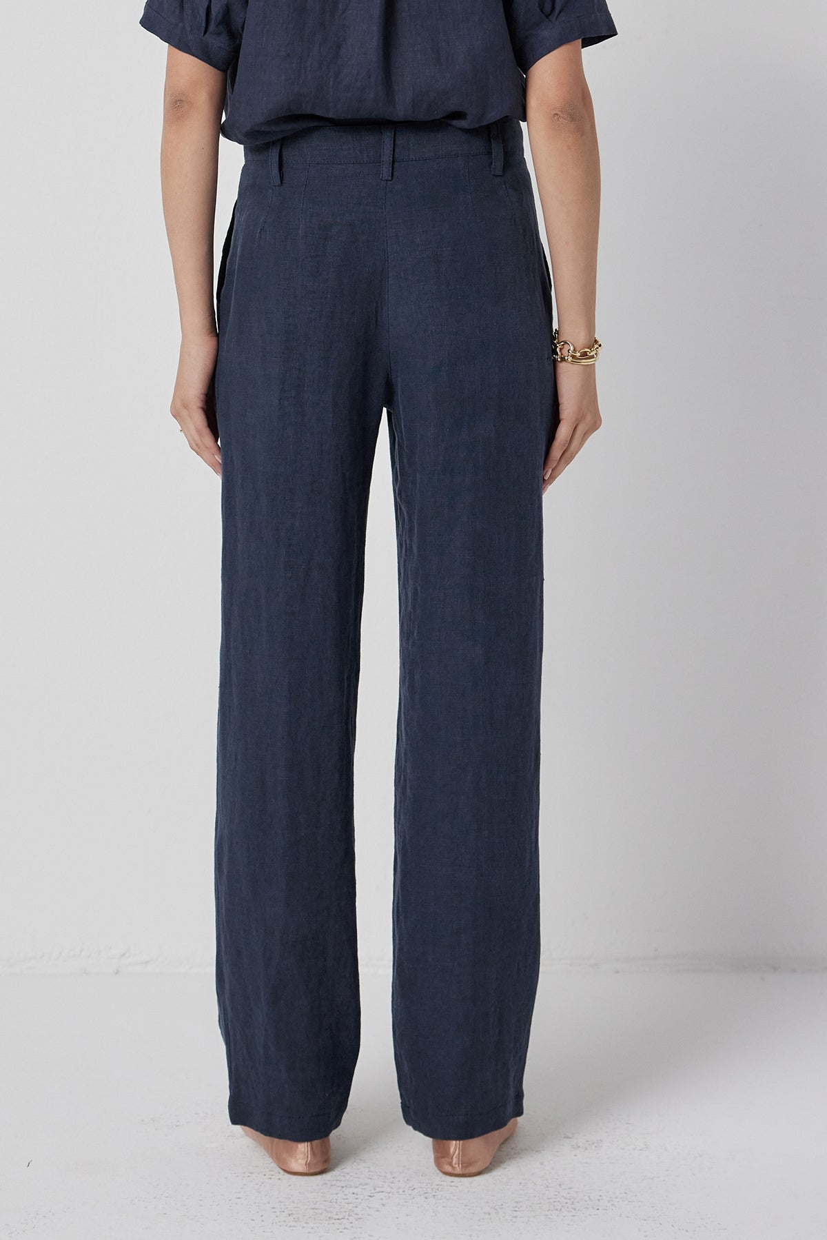   A person standing in Velvet by Jenny Graham's POMONA PANT trousers and a matching top with their hands partially tucked into pockets. 