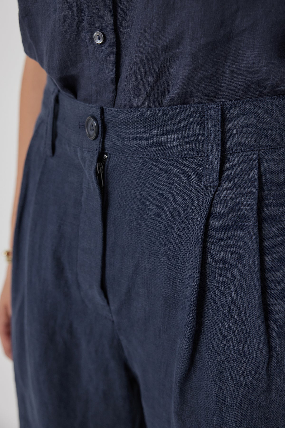   Close-up of a heavy-weight linen, blue POMONA PANT by Velvet by Jenny Graham with buttons and a waist belt. 