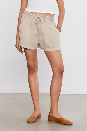 Woman standing in Velvet by Graham & Spencer's SUTTON HEAVY LINEN SHORT and tan ballet flats, cropped at the waist.