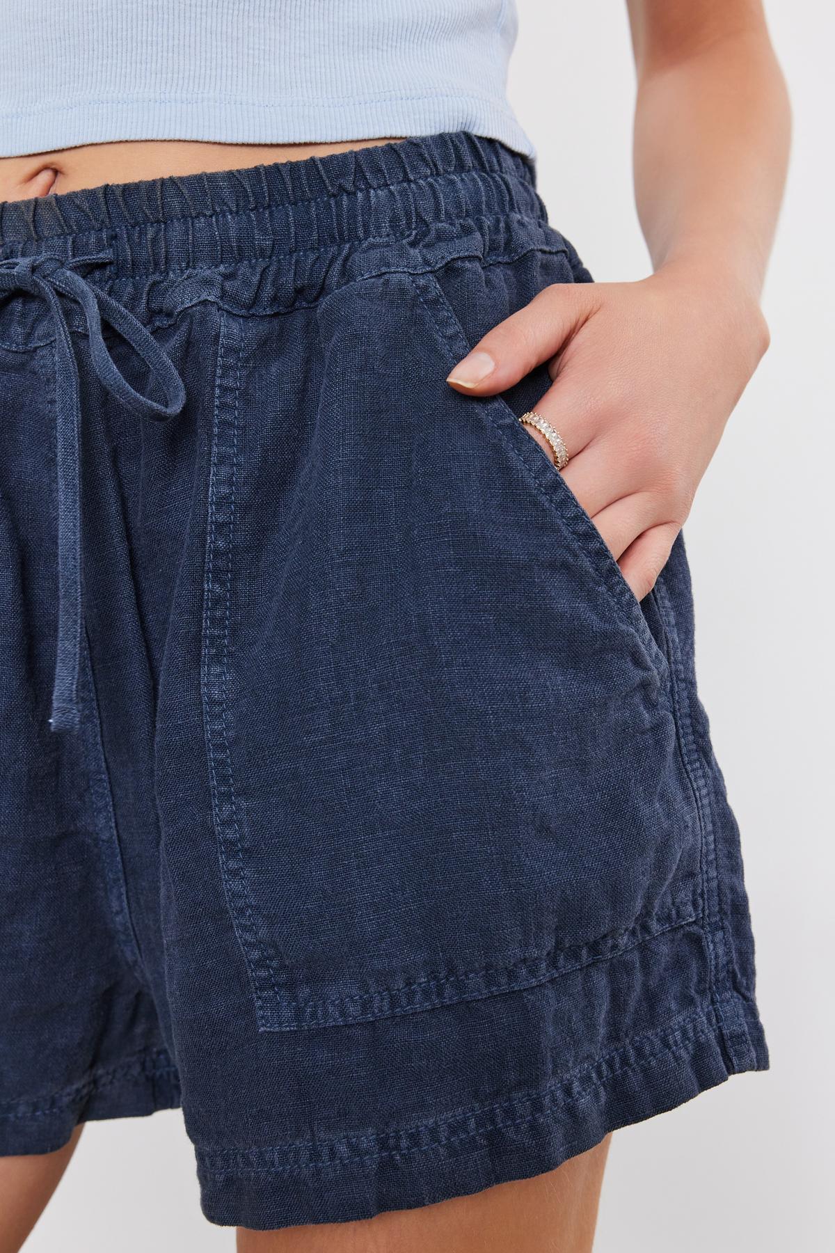   Close-up of a person wearing a Velvet by Graham & Spencer Sutton Heavy Linen Short, with a focus on the textured fabric and details like the waistband and pockets. 