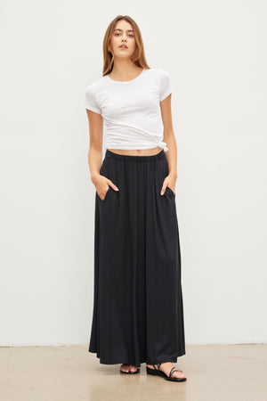 A woman wearing the Velvet by Graham & Spencer MALAYA MAXI SKIRT and a white t-shirt.