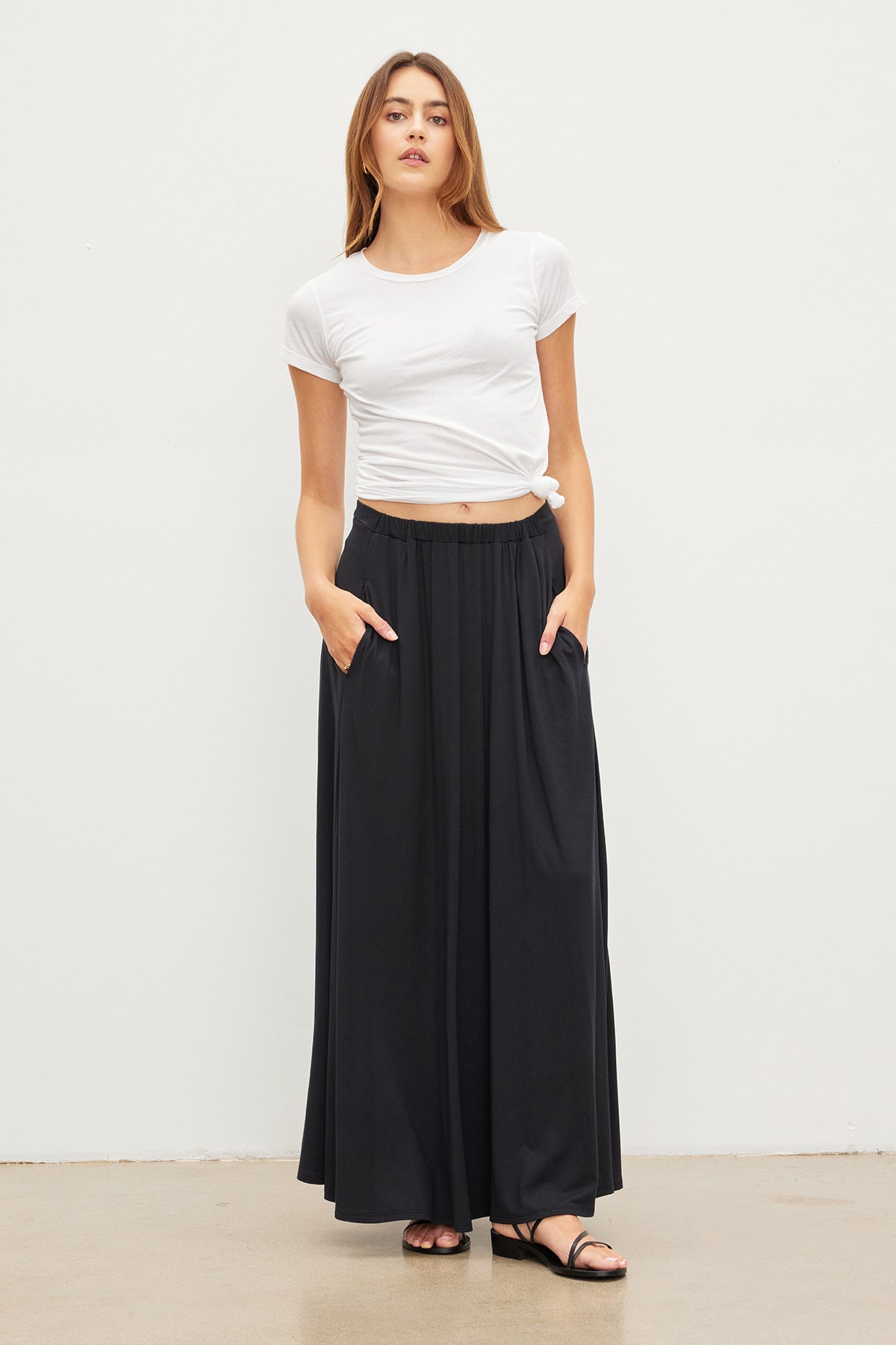   A woman wearing a Velvet by Graham & Spencer JEMMA GAUZY WHISPER FITTED CREW NECK TEE and black long skirt. 