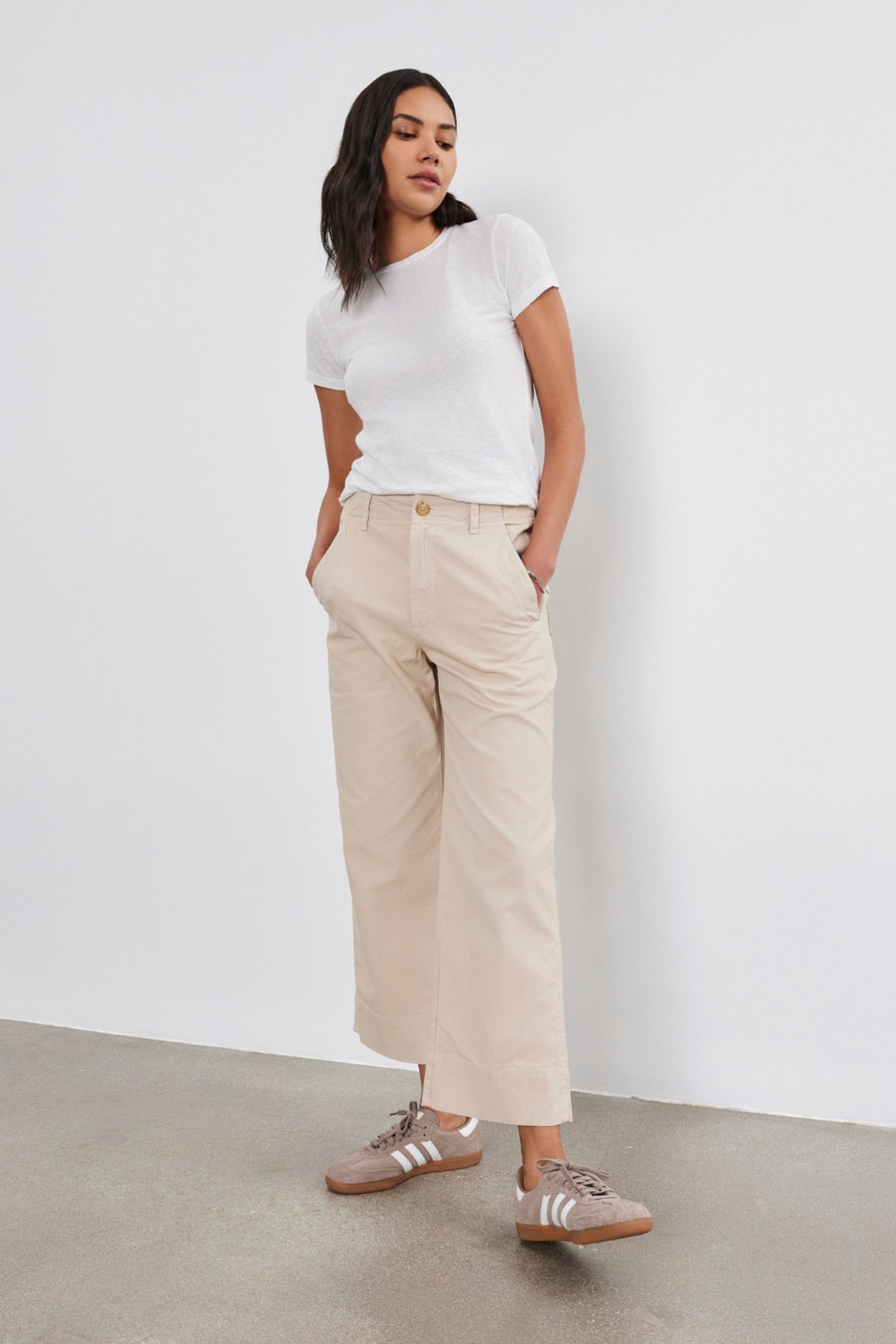 The model is wearing a white SIERRA CREW NECK TEE by Velvet by Graham & Spencer and beige cropped pants, giving off a retro vibe.-36594931859649