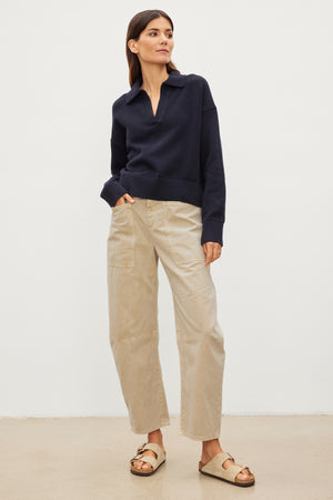 The model is wearing a navy sweater and Velvet by Graham & Spencer beige BRYLIE SANDED TWILL UTILITY PANT.