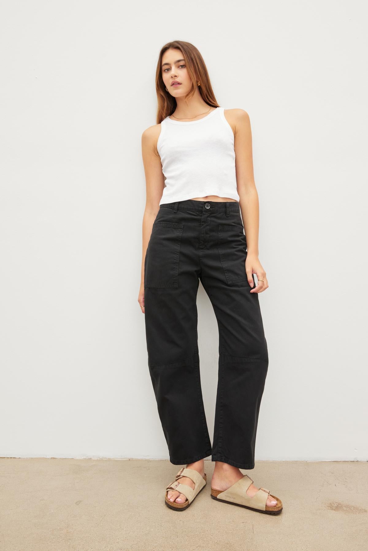   A woman wearing Velvet by Graham & Spencer's BRYLIE SANDED TWILL UTILITY PANT and a white tank top. 