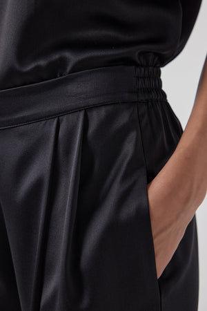 A close up of a woman's black silk Velvet by Jenny Graham charmwider leg Manhattan pants.