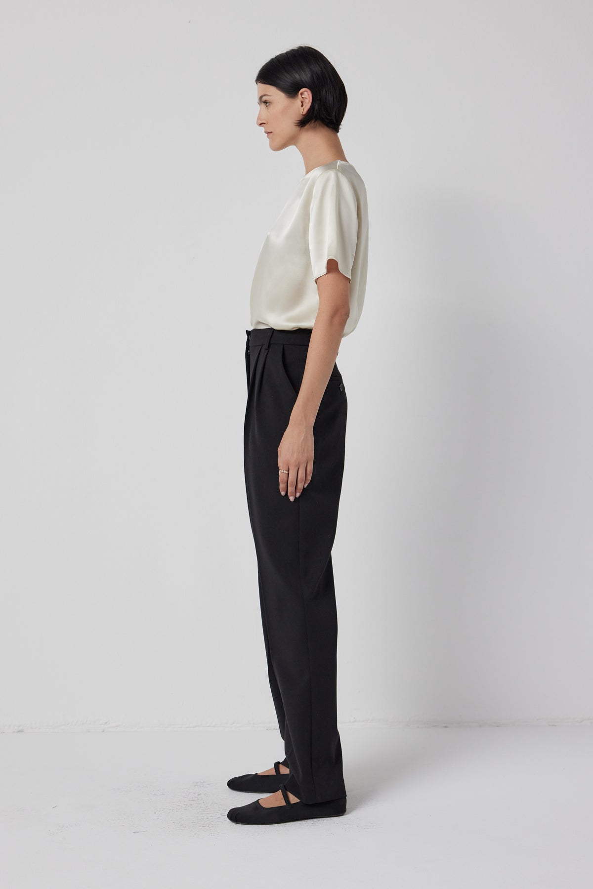 Woman in a business casual outfit with a Velvet by Jenny Graham PASADENA TOP and black trousers standing sideways against a white background, embodying timeless elegance.-36463793963201