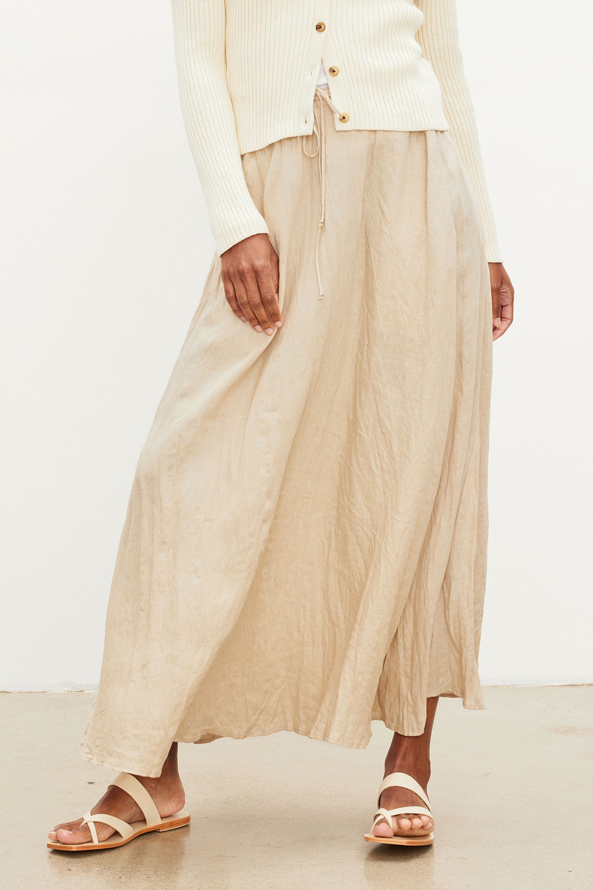   The model is wearing a Velvet by Graham & Spencer BAILEY LINEN MAXI SKIRT with an elastic drawstring waist and white sweater. 