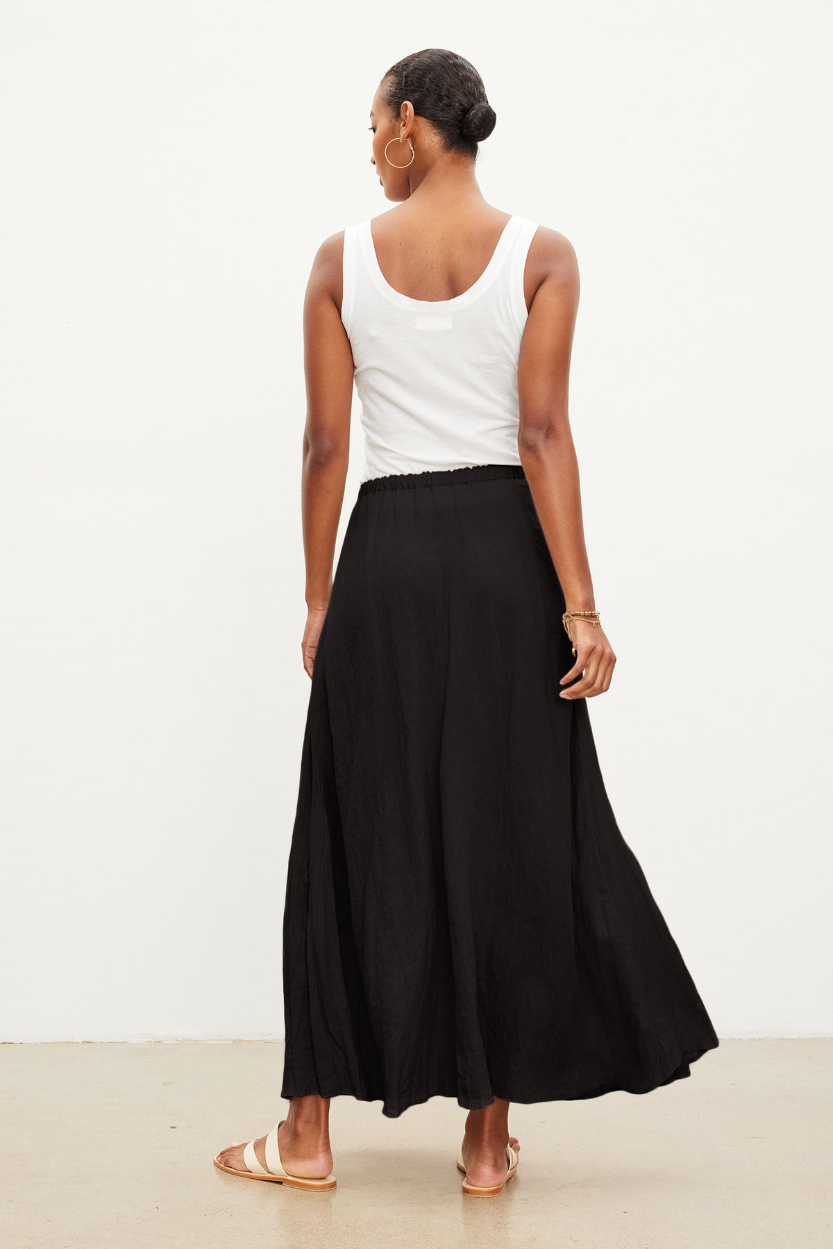 Person wearing a white sleeveless top, Velvet by Graham & Spencer BAILEY LINEN MAXI SKIRT with an elastic drawstring waist, and sandals, standing with their back facing the camera against a plain background.-37240025710785