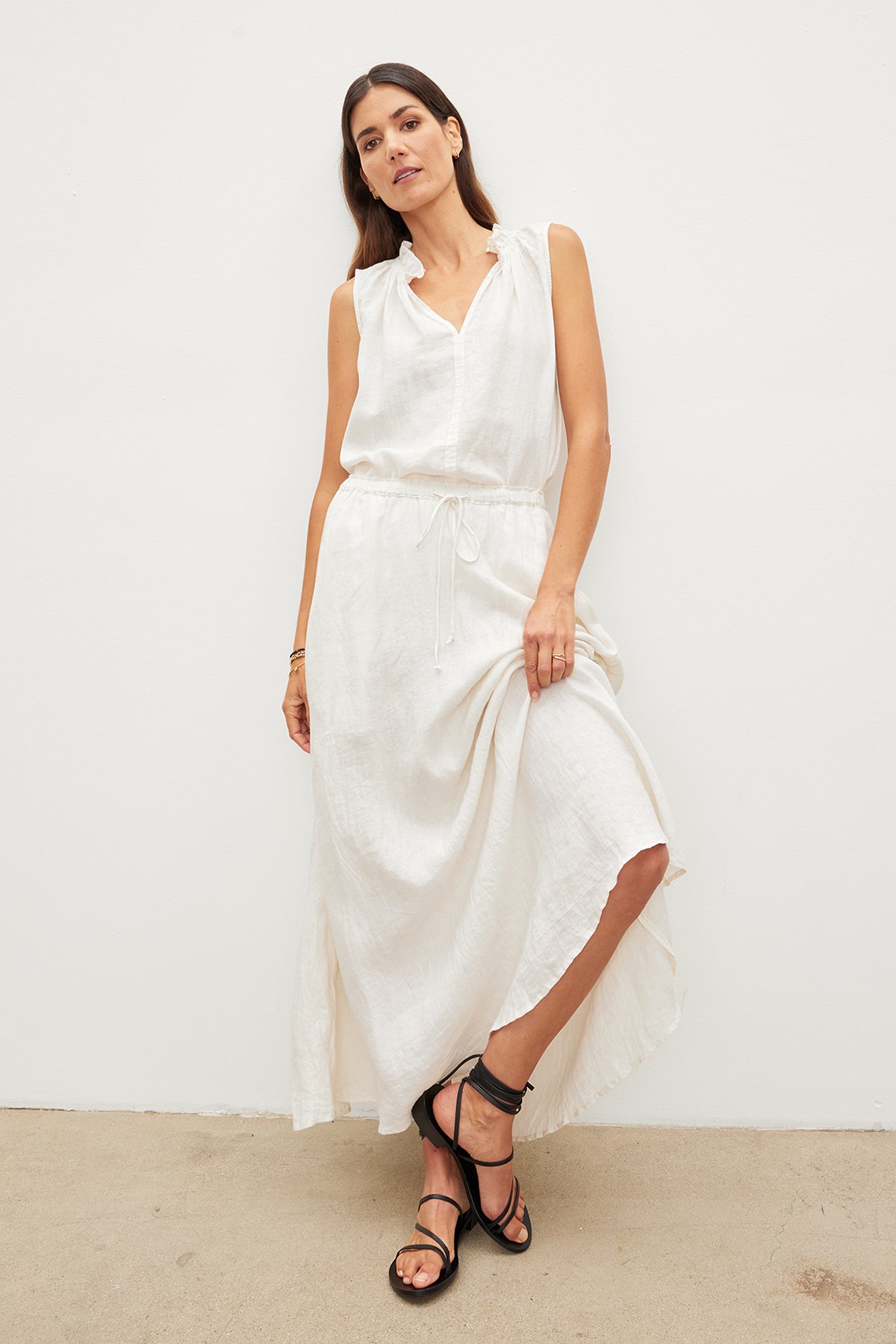   A woman wearing a white Velvet by Graham & Spencer MASIE LINEN TANK TOP and sandals. 