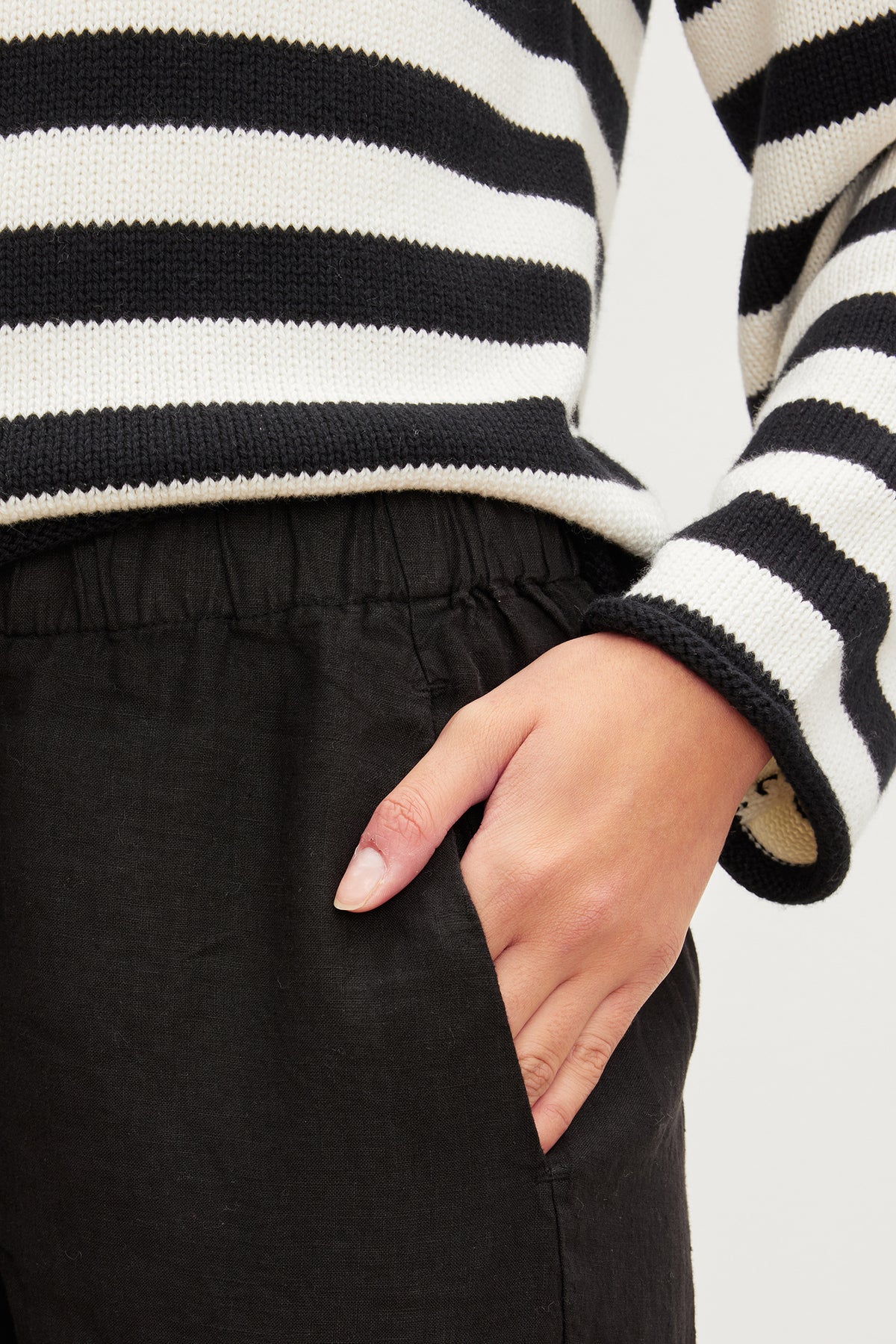   A woman wearing a black and white striped sweater and black Velvet by Graham & Spencer LOLA LINEN PANT. 