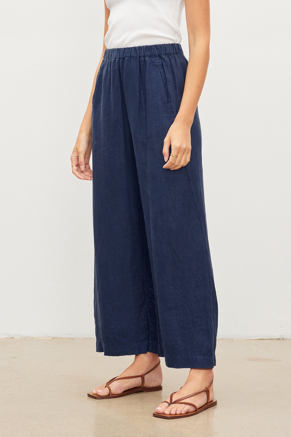   A woman wearing a pair of Velvet by Graham & Spencer LOLA LINEN PANT. The lightweight linen fabric provides comfort and breathability, while the elastic waist ensures a comfortable fit. 