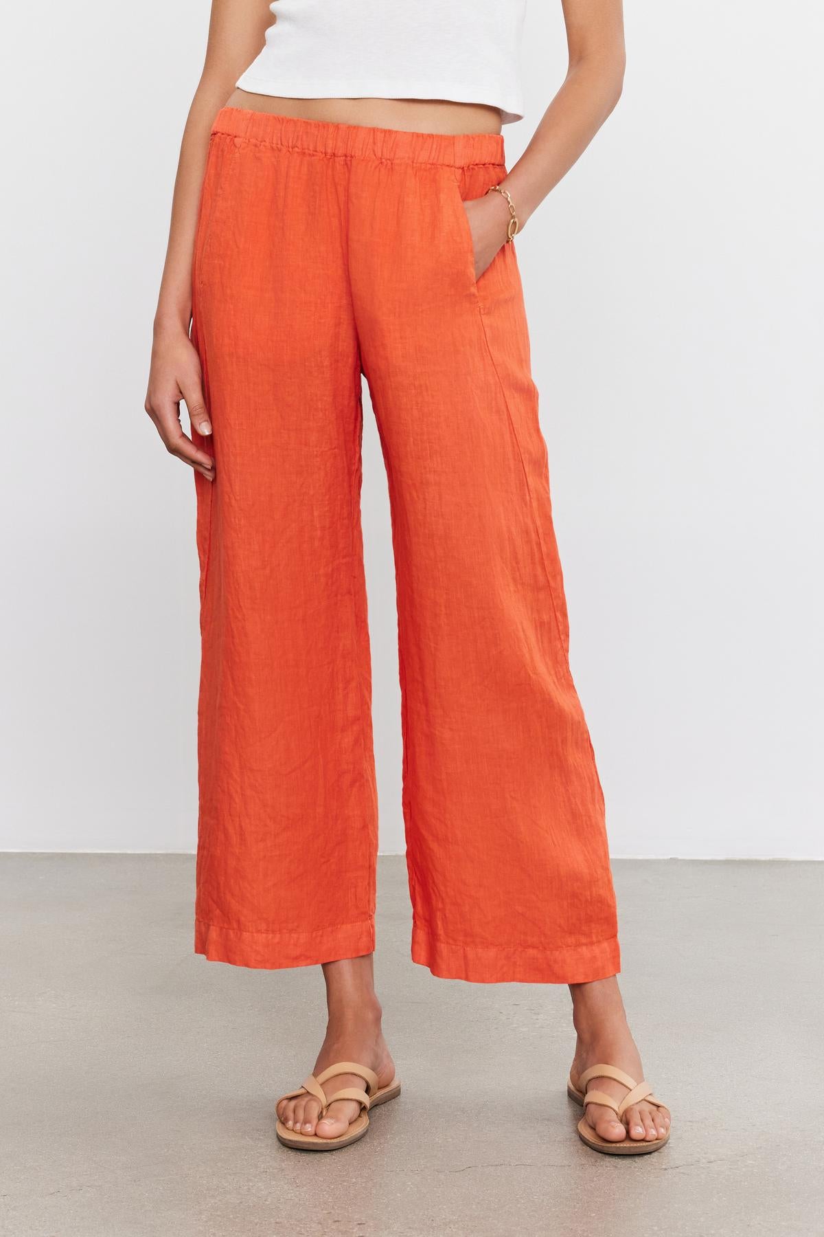Person in a white top and Velvet by Graham & Spencer LOLA LINEN PANT standing on a neutral background with one hand in a pocket.-36910043889857