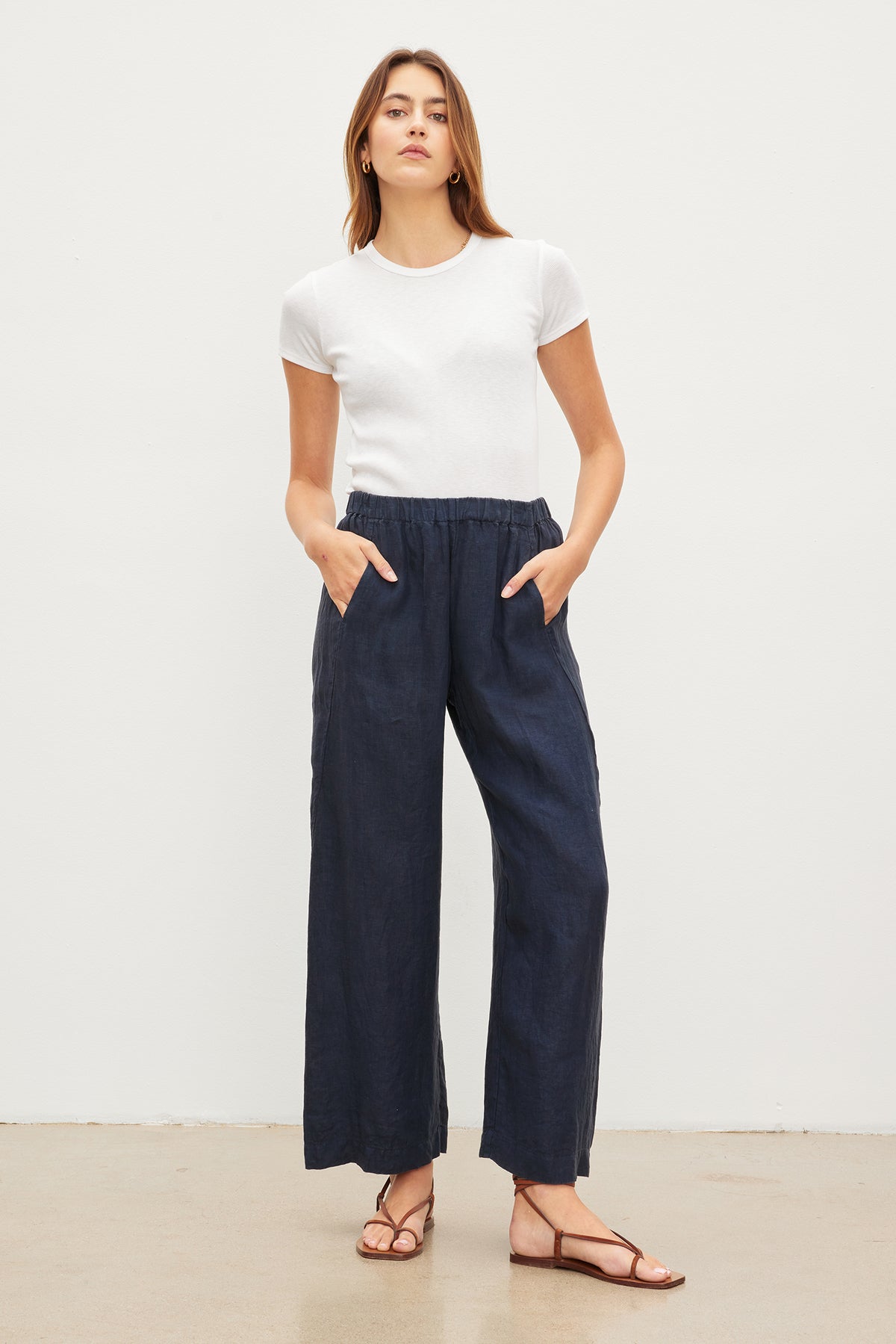   A woman in blue LOLA LINEN PANTS by Velvet by Graham & Spencer with an elastic waist. 