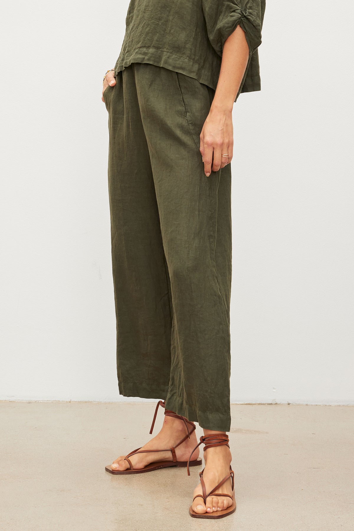 A woman in LOLA LINEN PANT by Velvet by Graham & Spencer and sandals is standing in front of a white wall.-36002694332609
