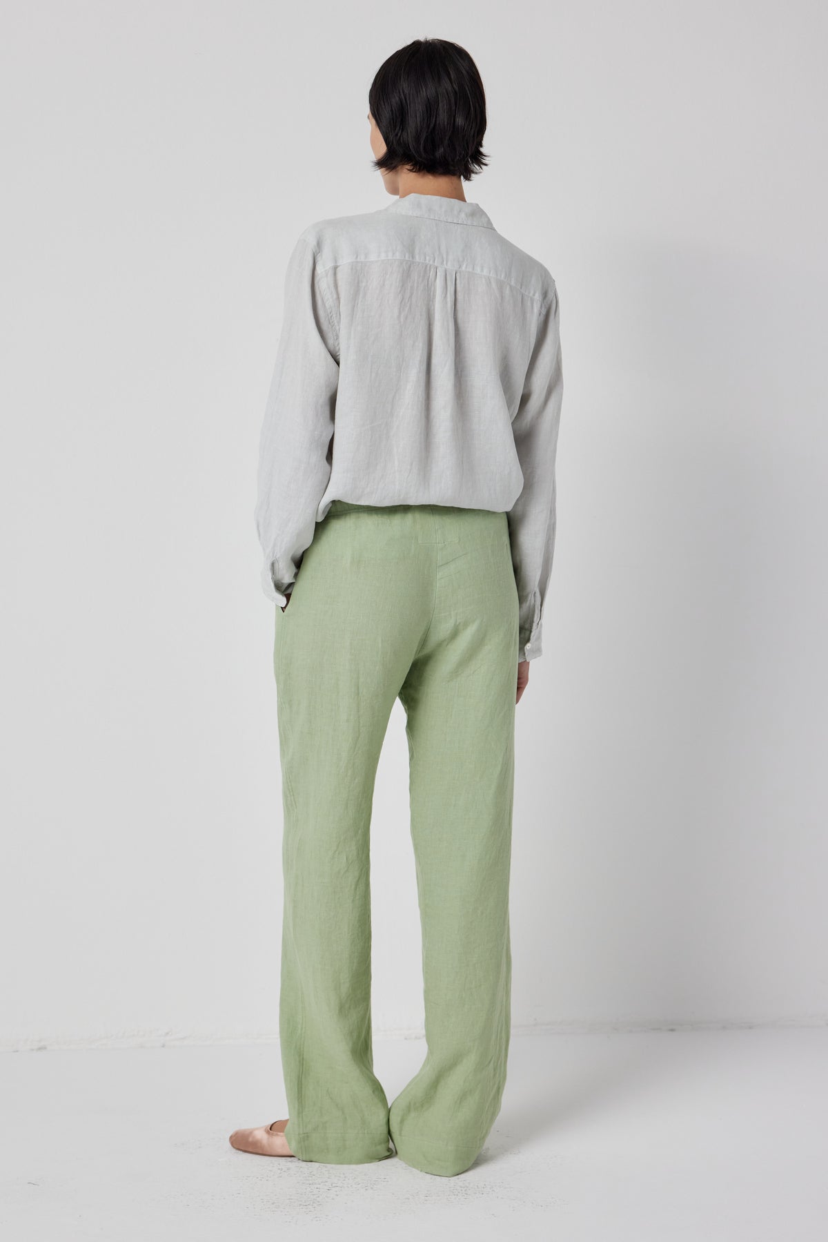   Woman standing with her back to the camera, wearing a gray blouse and green relaxed fit Velvet by Jenny Graham PICO PANT. 