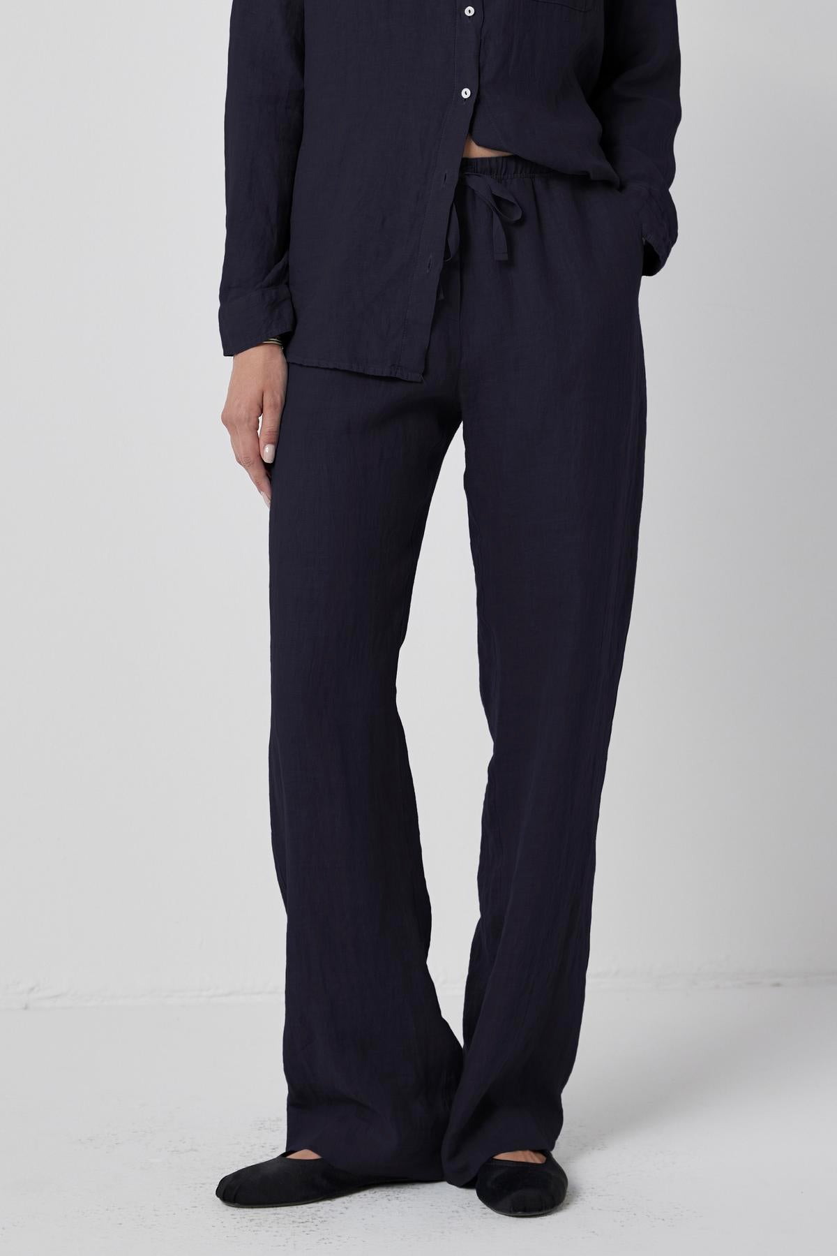   A person wearing a dark navy long-sleeve shirt and matching Velvet by Jenny Graham PICO LINEN PANT with an elastic waist, standing against a plain white background. Only the torso and legs are visible. 