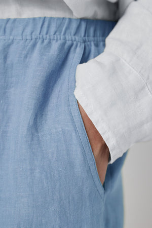 Close-up of a person wearing Velvet by Jenny Graham's PICO LINEN PANT in light blue, and a white shirt, focusing on the hip area where the shirt is tucked in slightly.