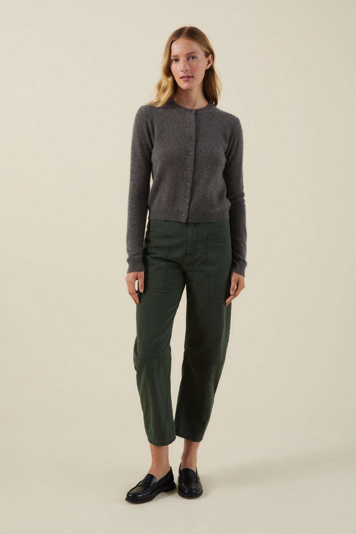 A woman wearing an AYLINA CASHMERE CARDIGAN in charcoal gray, dark green cropped utility pants, and black loafers.