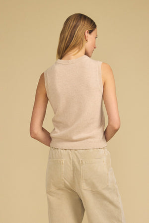 A person stands with their back to the camera, wearing the IVANA CASHMERE SWEATER VEST by Velvet by Graham & Spencer and light beige pants, set against a plain beige background.