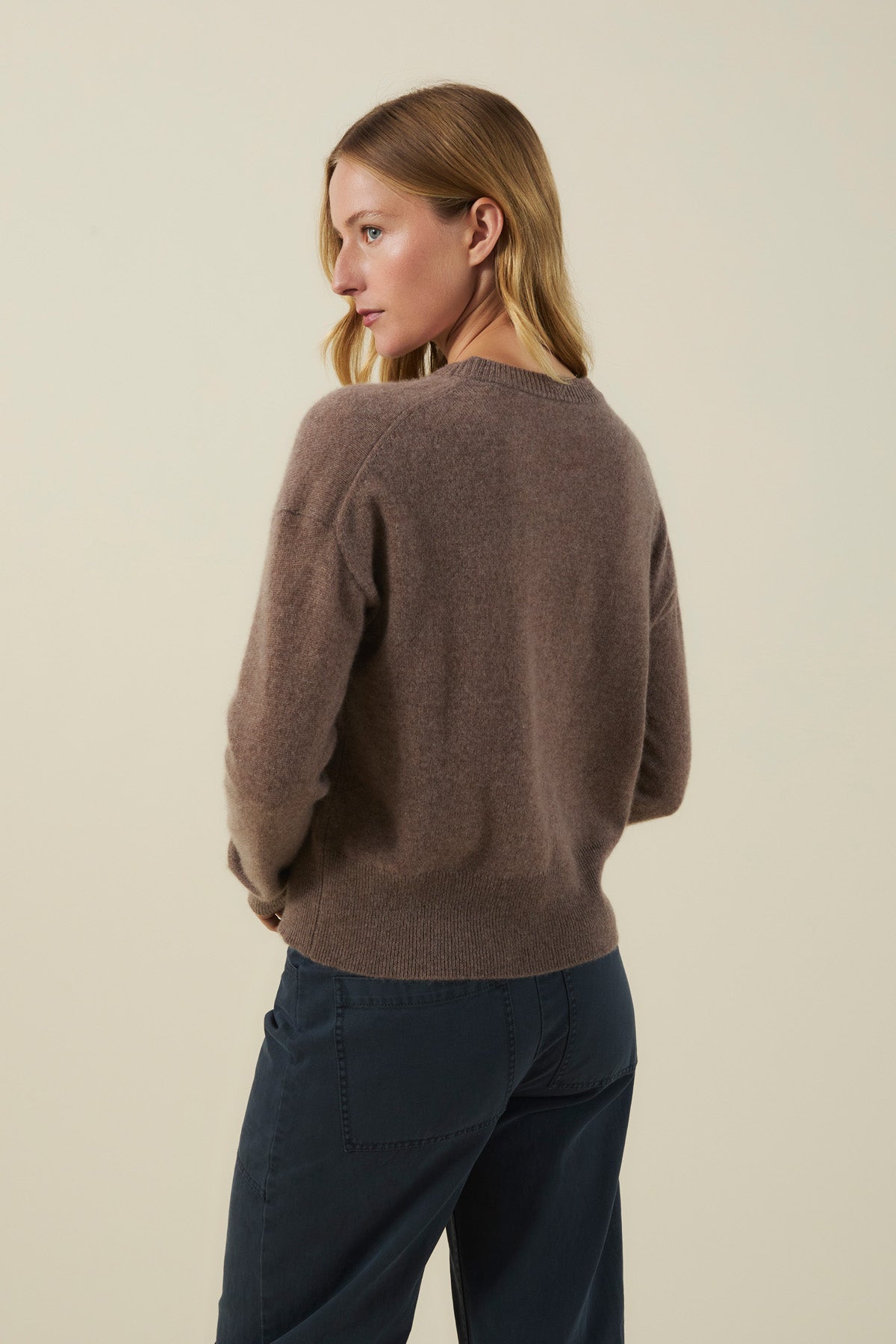 A person seen from behind wearing an ALBA CASHMERE SWEATER with a crew neckline and dark pants.-46498787262657