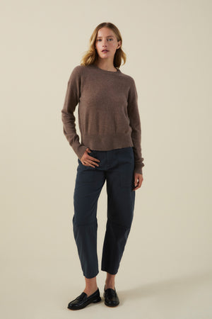 Woman wearing an ALBA CASHMERE SWEATER in brown, dark blue utility-style pants, and black loafers.