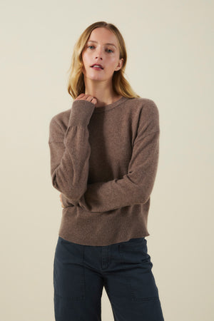 A woman wearing a brown, soft knit ALBA CASHMERE SWEATER by Velvet by Graham & Spencer with dark pants.