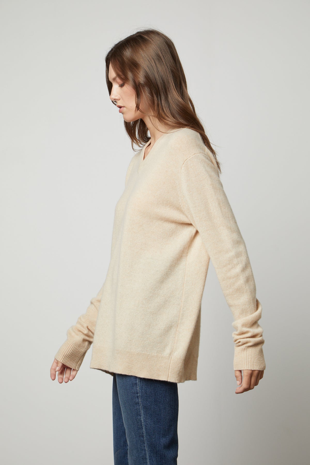 The model is wearing an oversized Velvet by Graham & Spencer Harmony Cashmere V-Neck Sweater and jeans.-35655722762433