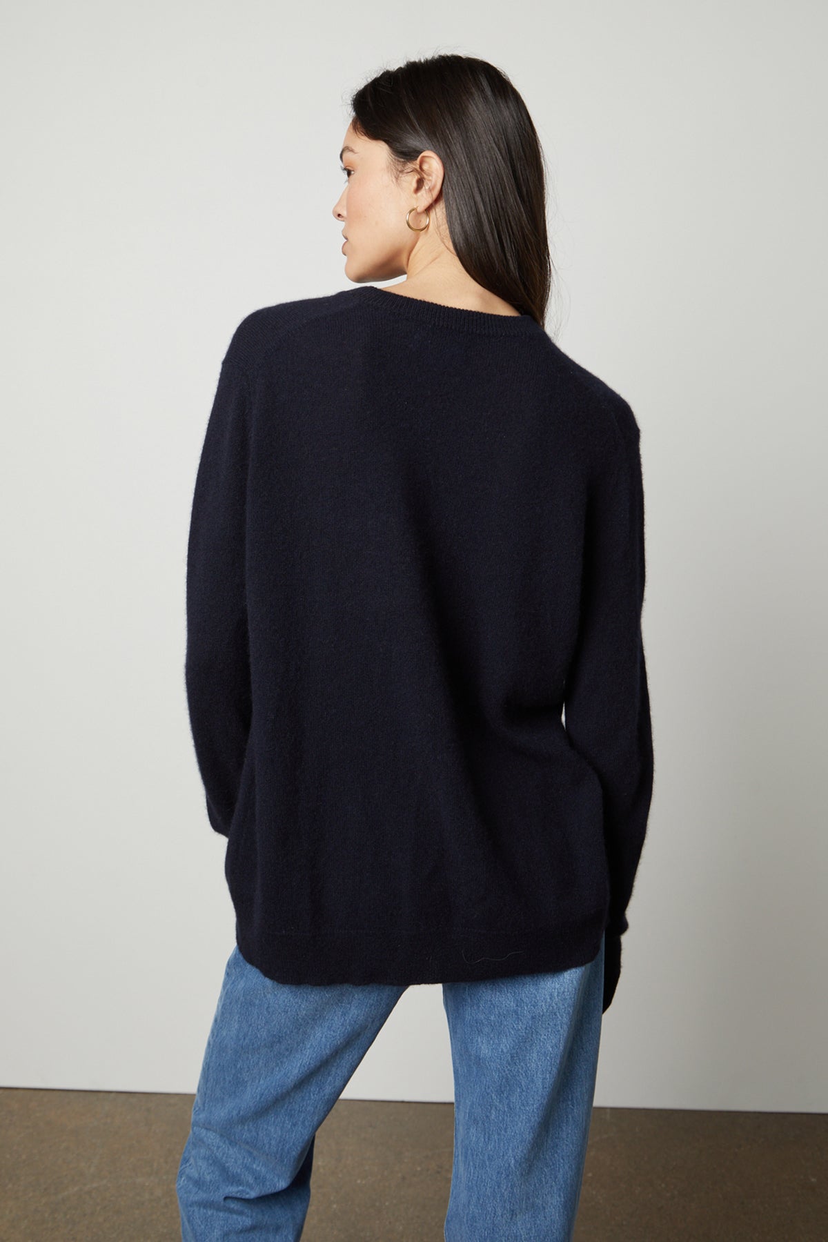 The back view of a woman wearing a Velvet by Graham & Spencer HARMONY CASHMERE V-NECK SWEATER and jeans.-26897789714625