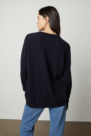 The back view of a woman wearing a Velvet by Graham & Spencer HARMONY CASHMERE V-NECK SWEATER and jeans.