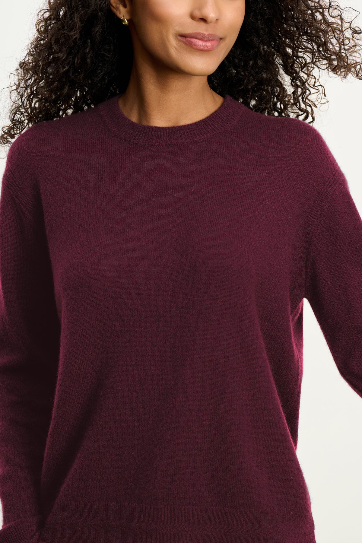A woman wears the Velvet by Graham & Spencer CRYSTAL CASHMERE SWEATER—a long-sleeved, dark burgundy cashmere piece with ribbed trims—shown from shoulders to hips against a plain background.-39838379376833