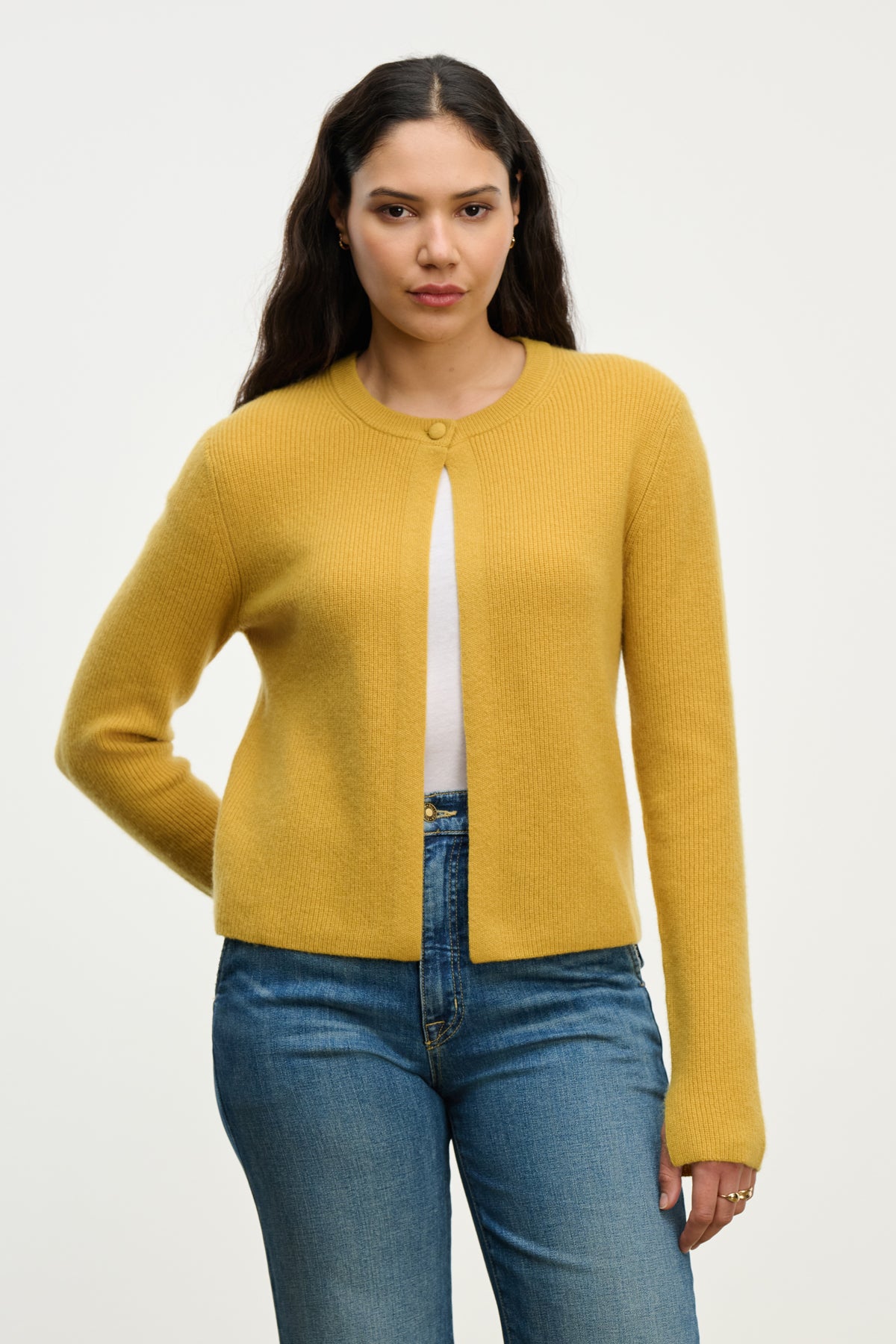 A woman wears the TINA CASHMERE CARDIGAN by Velvet by Graham & Spencer in yellow over a white top and blue jeans, standing against a plain white background.-39814940328129