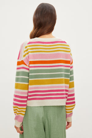 The back view of a woman wearing a Velvet by Graham & Spencer ANNY CASHMERE STRIPED CREW NECK SWEATER with multi-colored stripes.