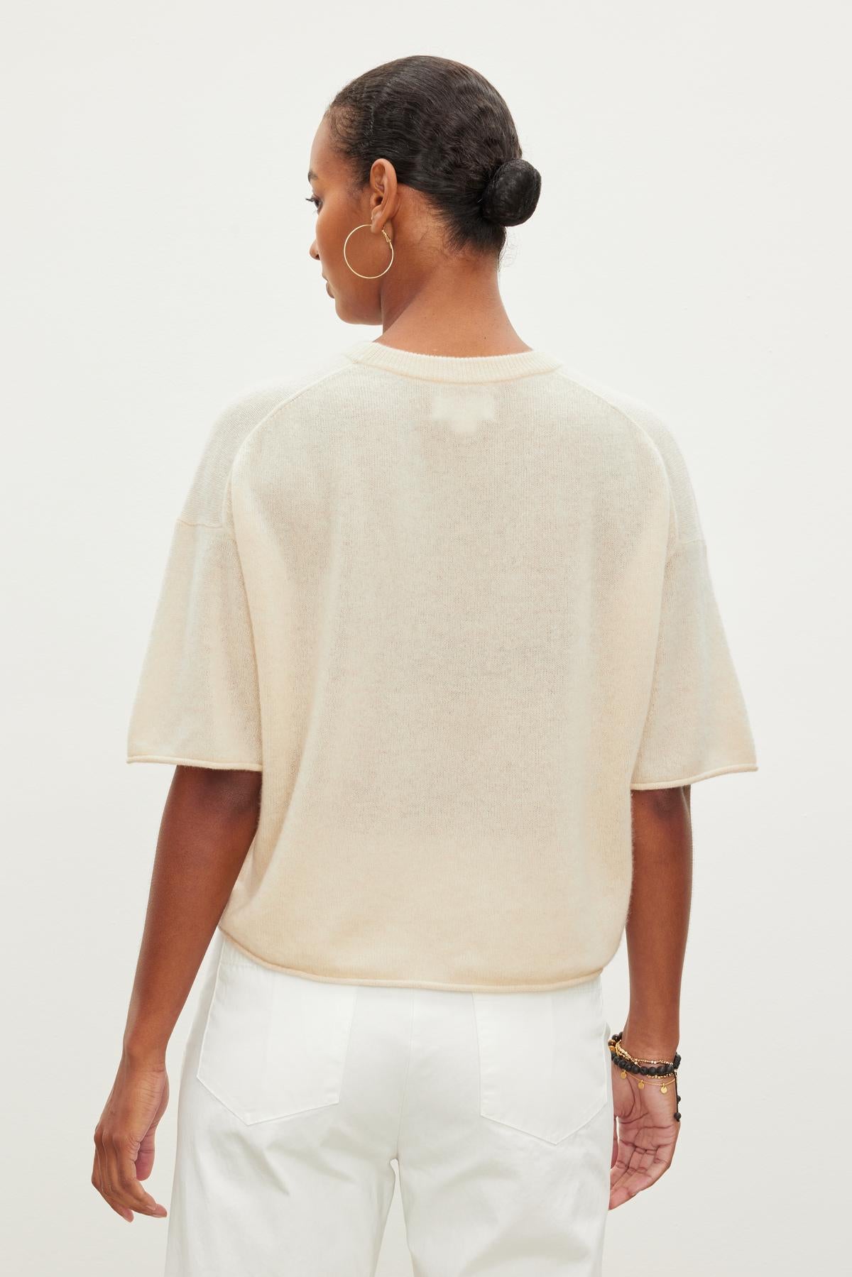   The back view of a woman wearing a modern Velvet by Graham & Spencer BLAKE CASHMERE CREW NECK SWEATER and white pants. 