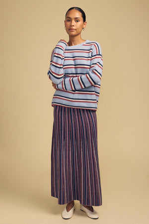 A person wearing a blue striped cashmere blend crewneck sweater, a Velvet by Graham & Spencer DESIREE FLARED SKIRT, and cream-colored flats.