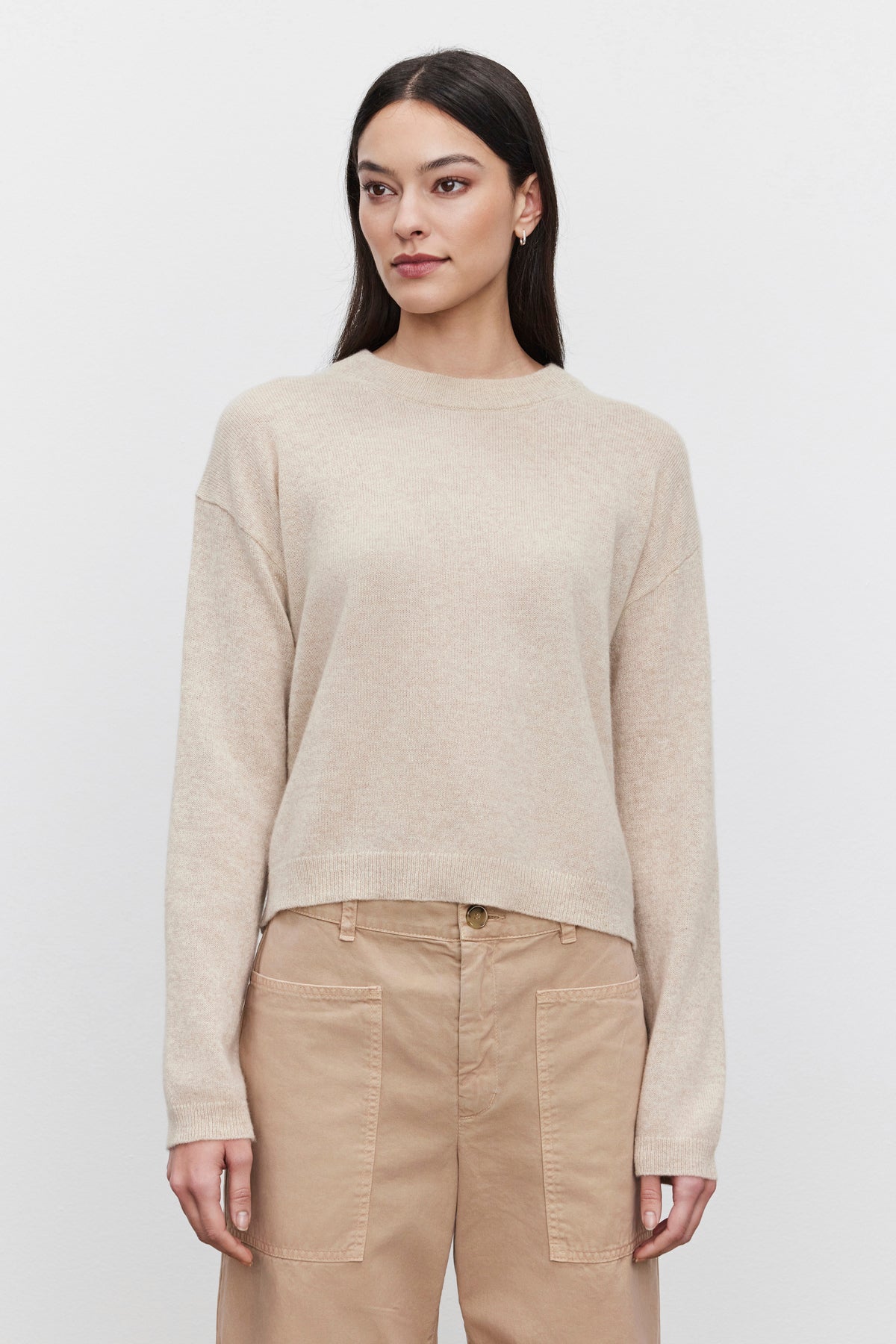   A person is elegantly dressed in the BROOKLYN CASHMERE SWEATER by Velvet by Graham & Spencer, along with matching pants, exuding a contemporary look against a plain white background. 