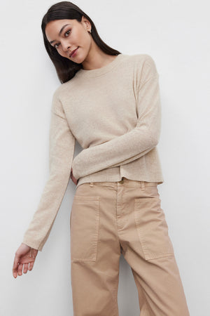 A person wearing the BROOKLYN CASHMERE SWEATER from Velvet by Graham & Spencer and light brown pants stands against a plain white background, showcasing a contemporary look.