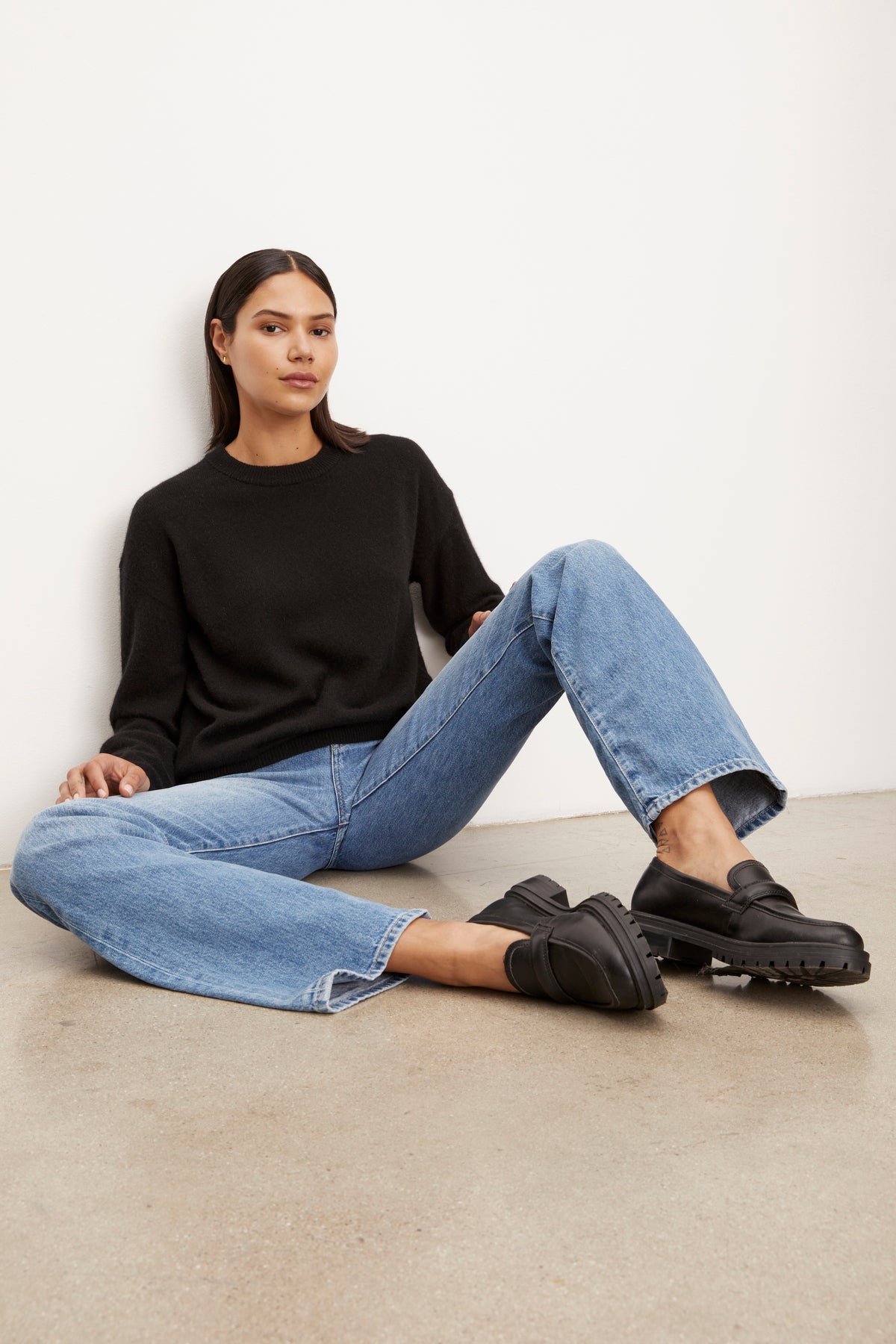 A woman is sitting on the floor in black jeans and a Velvet by Graham & Spencer BRYNNE CASHMERE CREW NECK SWEATER.-26883604316353