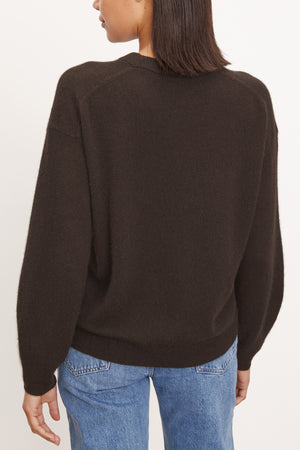 A person wears the BRYNNE CASHMERE SWEATER by Velvet by Graham & Spencer in dark brown, paired with blue jeans, shown from the back against a plain light background.