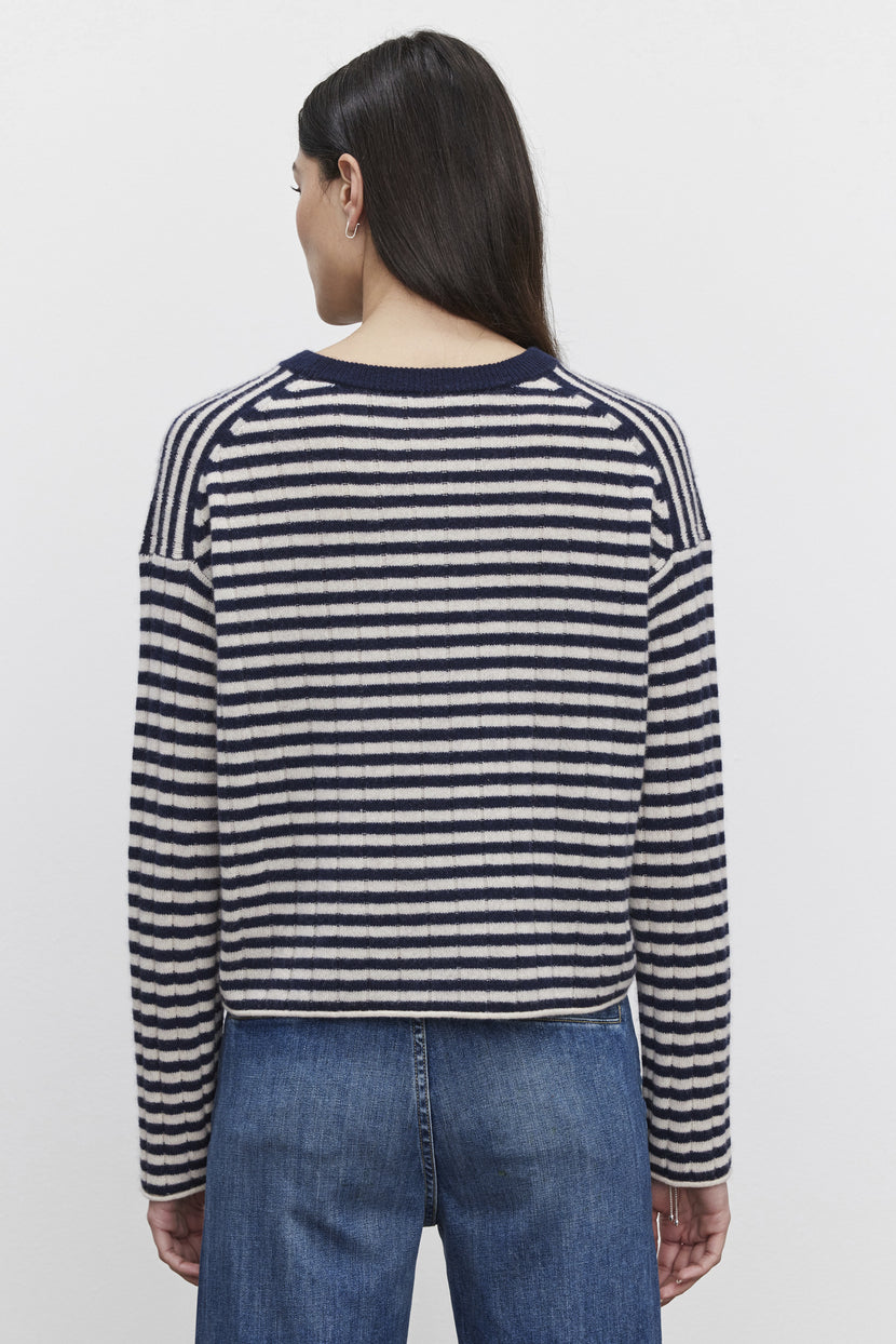 A person, seen from behind, dons the MONICA CASHMERE SWEATER by Velvet by Graham & Spencer. This navy and white striped piece with long sleeves complements their dark hair and denim jeans, embodying luxurious comfort.