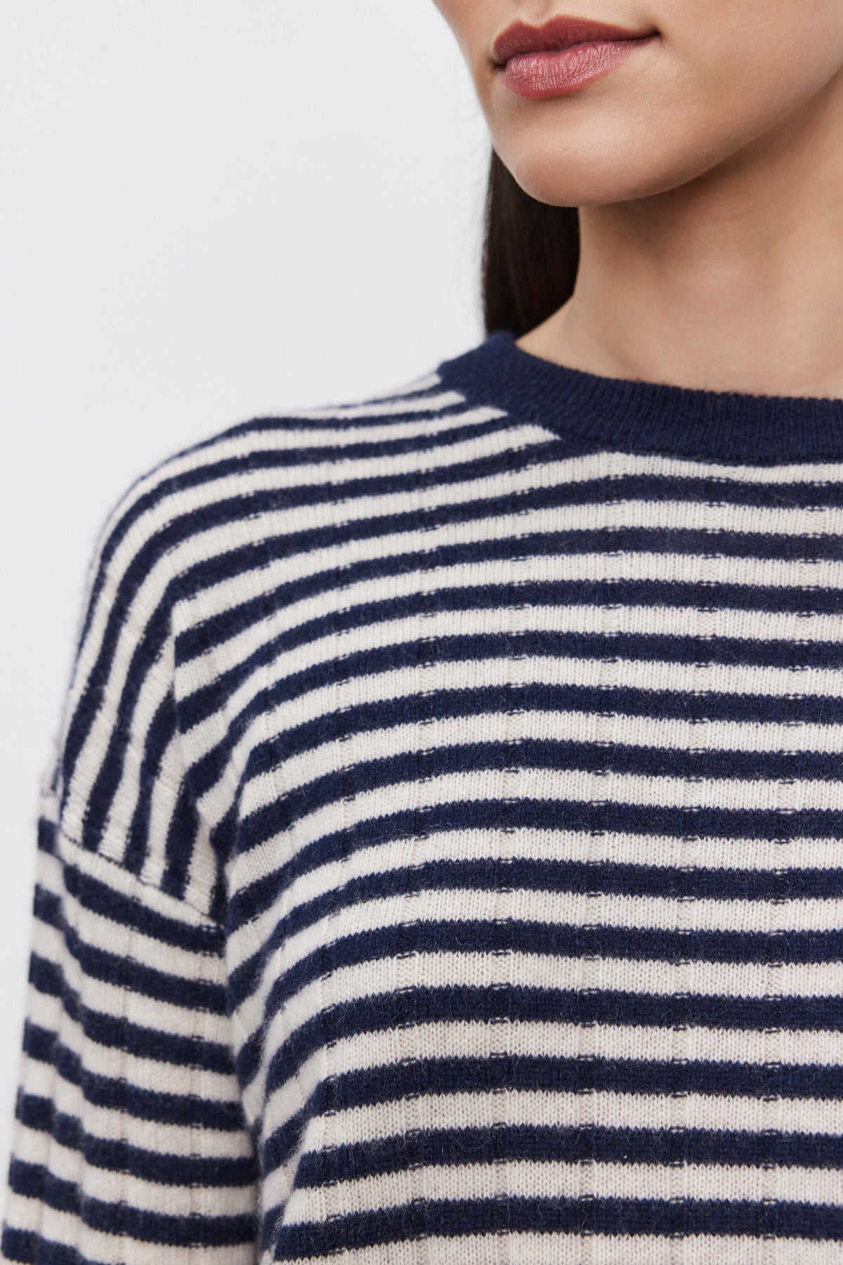   Close-up of a person wearing the MONICA CASHMERE SWEATER by Velvet by Graham & Spencer, a blue and white striped cashmere sweater, cropped to show neck and part of the face without any distinct facial features. This wardrobe essential offers both comfort and style. 