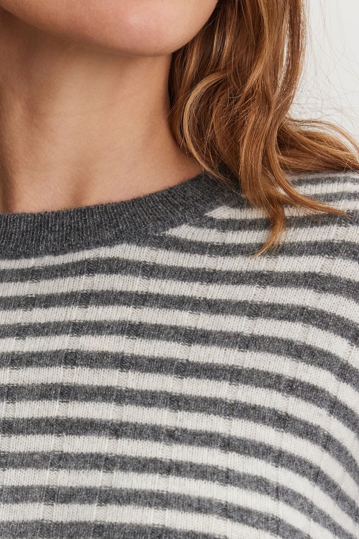 Close-up of a person wearing the MONICA CASHMERE SWEATER by Velvet by Graham & Spencer, showcasing luxurious comfort in gray and white stripes.-38301405446337