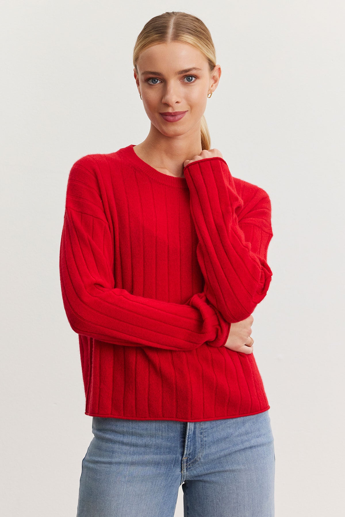 A person wearing the MONICA CASHMERE SWEATER by Velvet by Graham & Spencer, a true wardrobe essential, and blue jeans stands against a plain background.-38301411442881