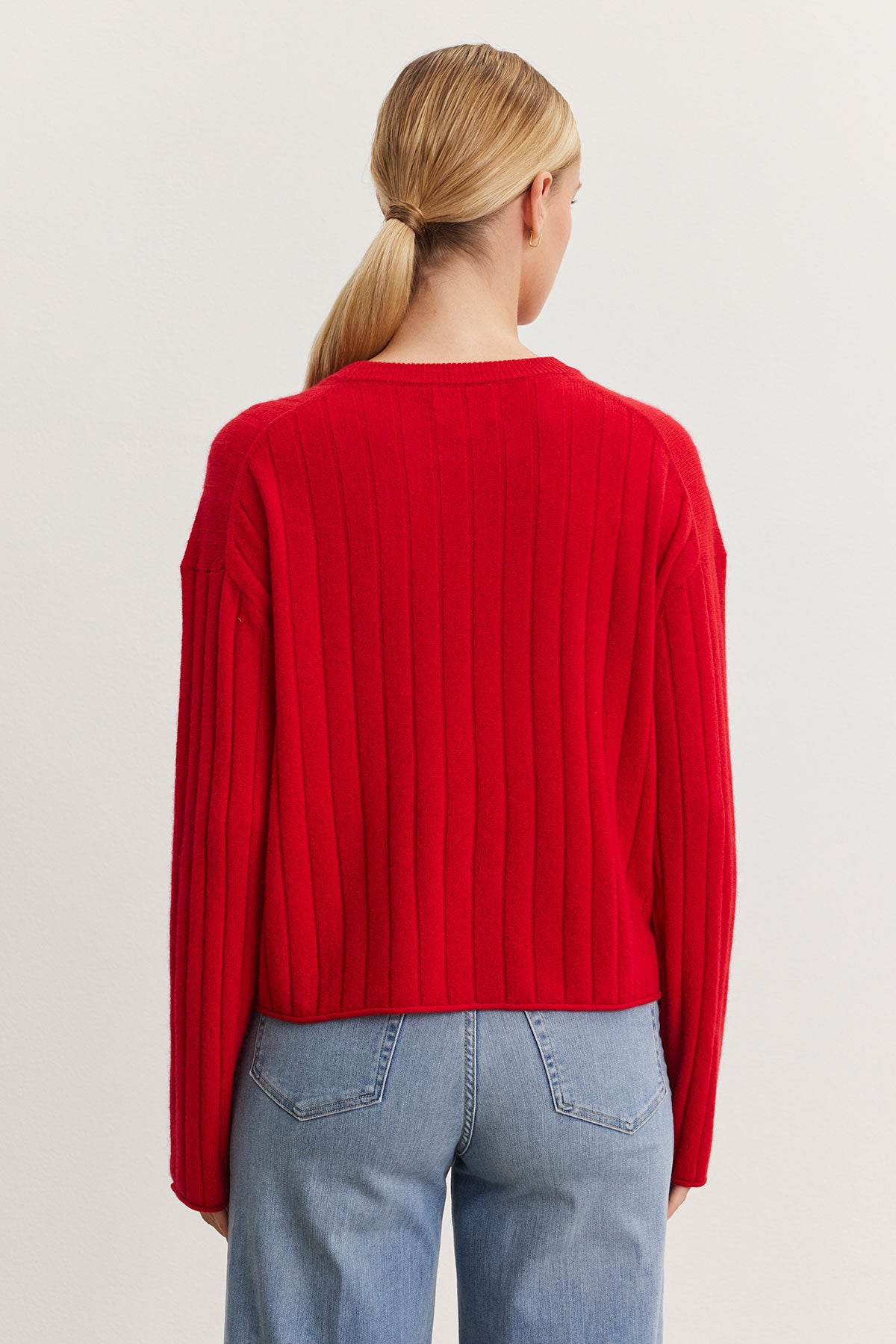   The individual is wearing a red Monica Cashmere Sweater by Velvet by Graham & Spencer and blue jeans, facing away from the camera. 