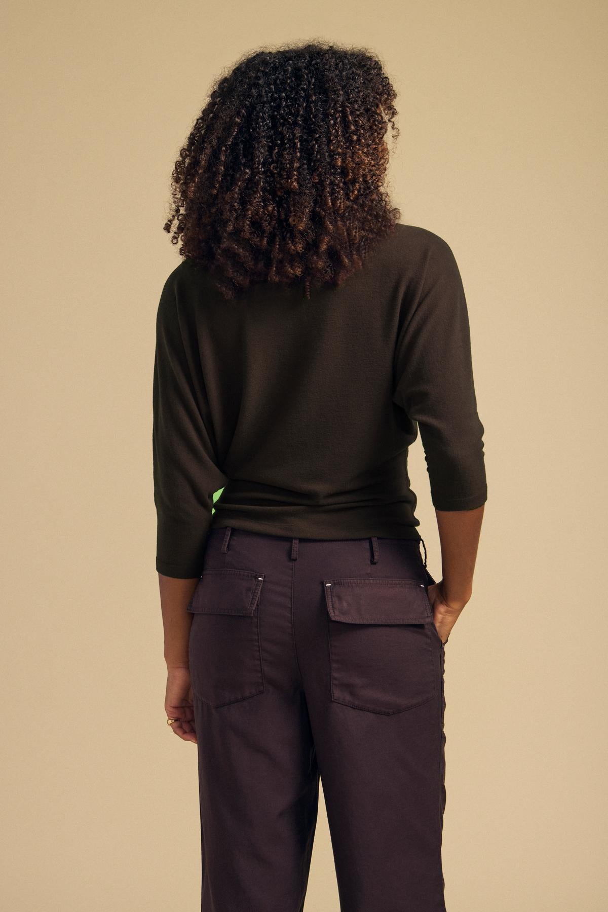 A person seen from the back wearing a dark green CECILIA TOP with dolman sleeves and dark cargo pants.-46319788916929